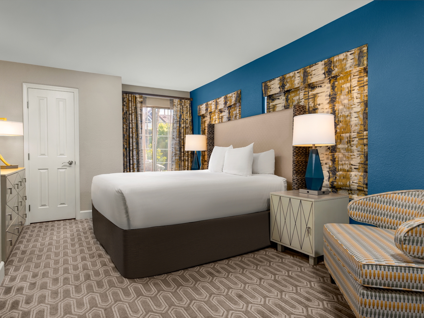 Bright, modern bedroom with bold hues and cozy seating.
