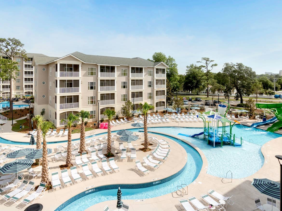 Lazy river with tubes winds by resort buildings.