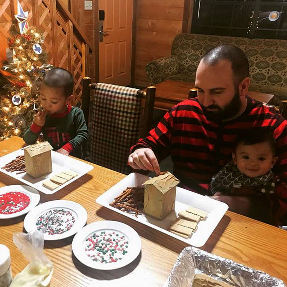 Guests dressed and holiday jammies sit at our Holly Lake resort kitchen table making gingerbread houses.
