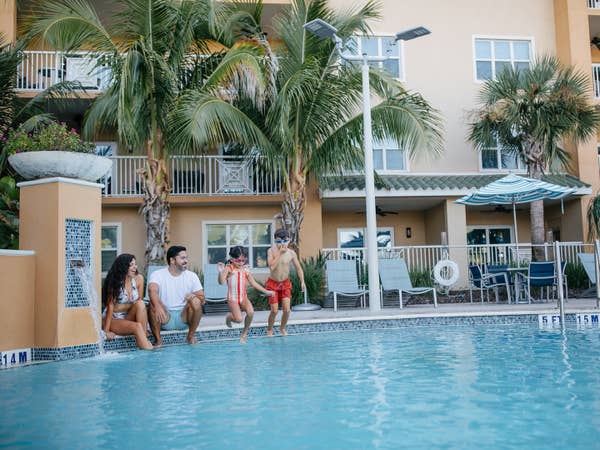 Family of four sitting on edge of pool at Cape Canaveral Beach Resort in Florida.