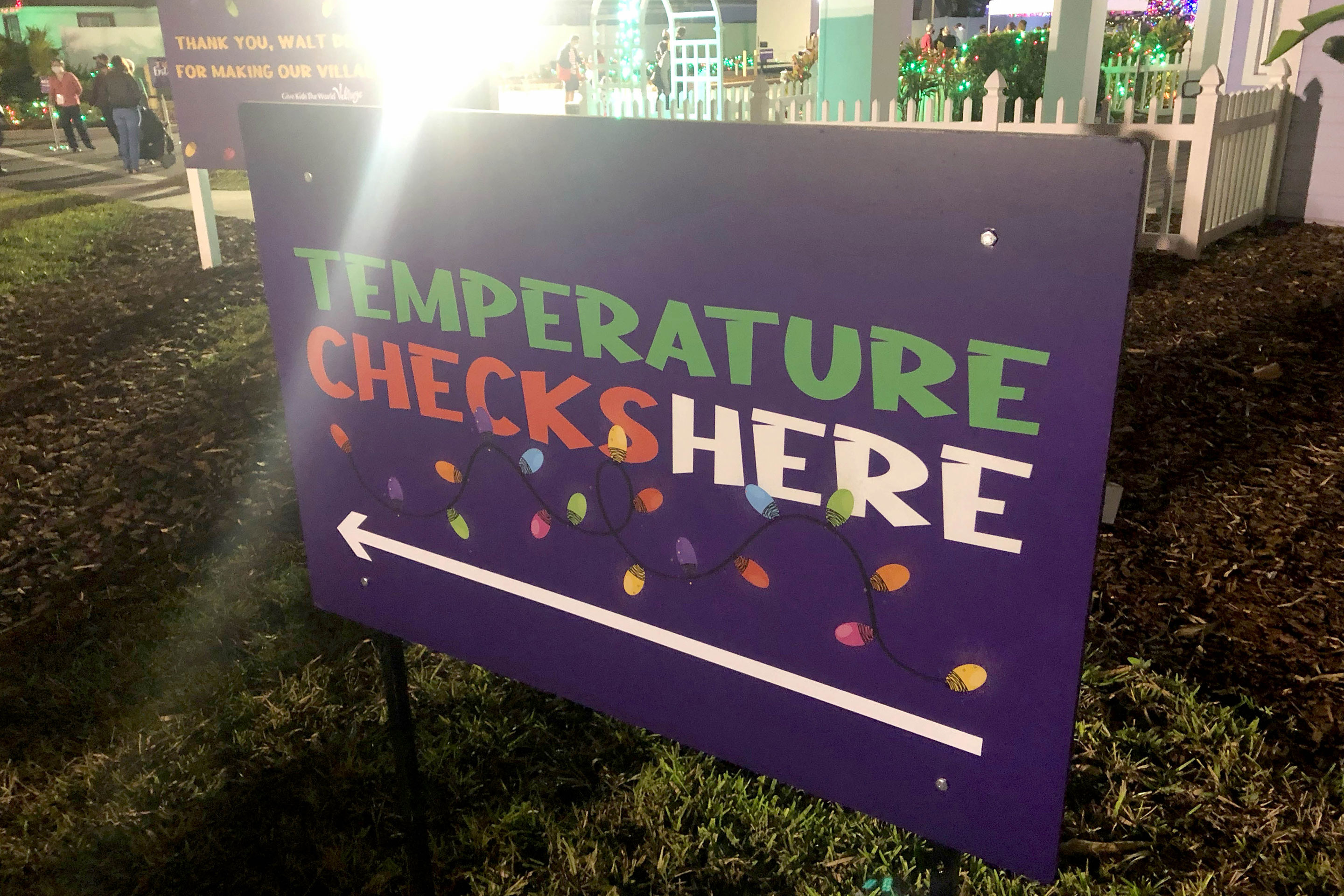 Purple signage indicating 'Temperature Checks Here' for COVID safety measures.