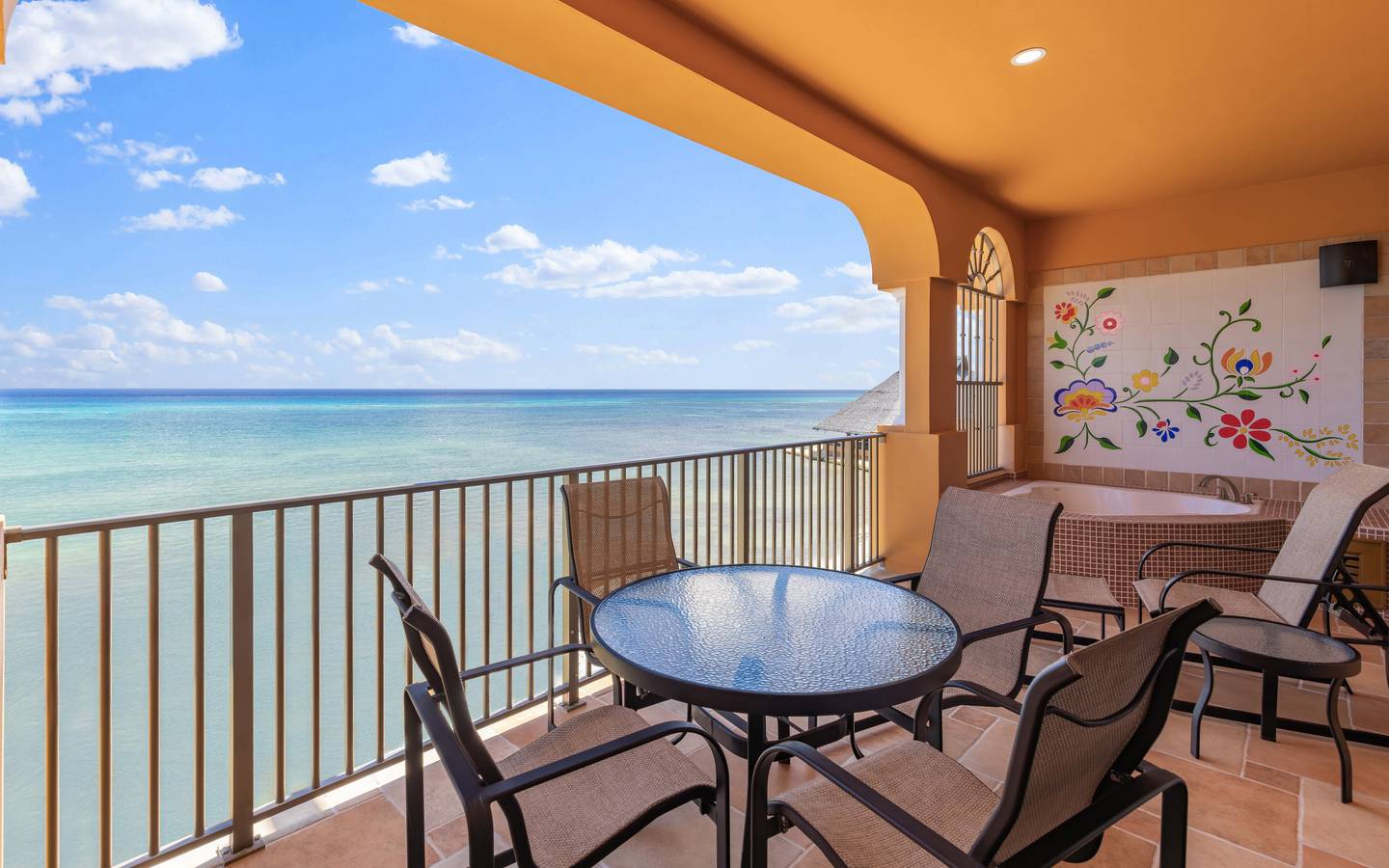 Oceanfront balcony with table, chairs, and soaking tub.