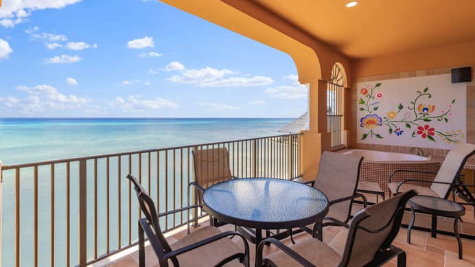 Oceanfront balcony with table, chairs, and soaking tub.