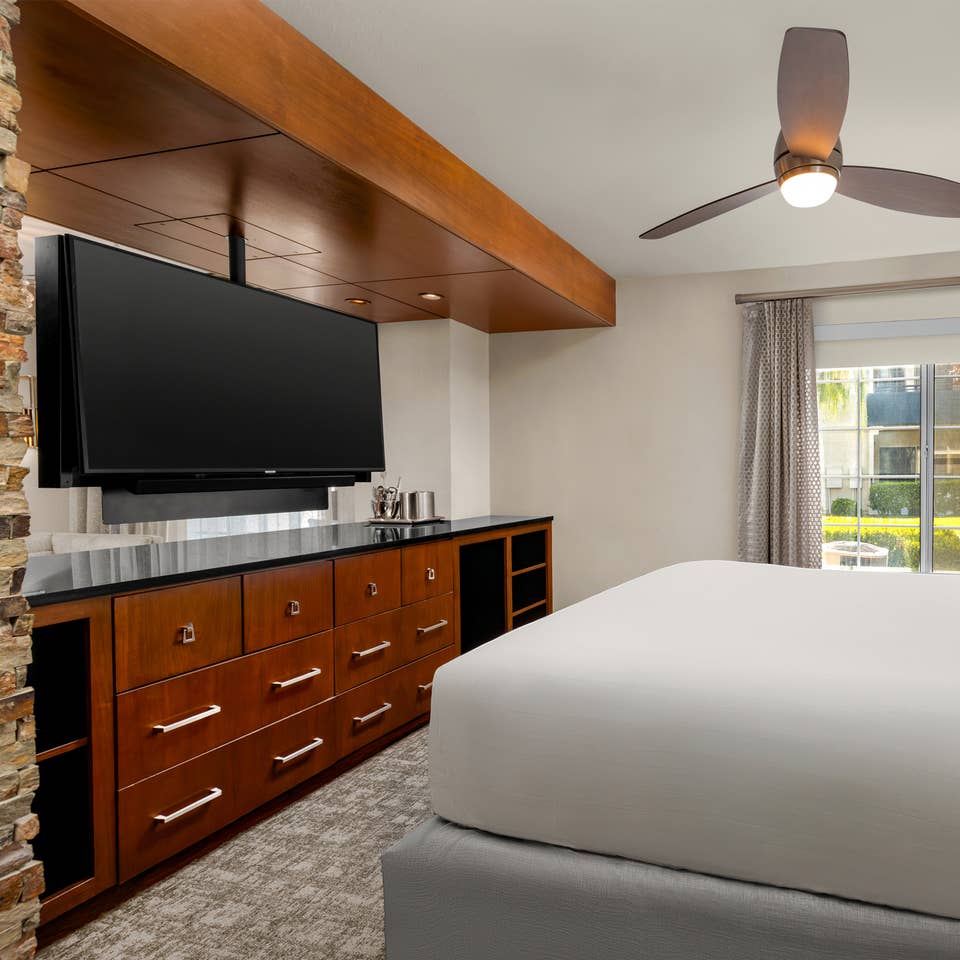 Spacious bedroom with plush bedding and modern in-room entertainment.