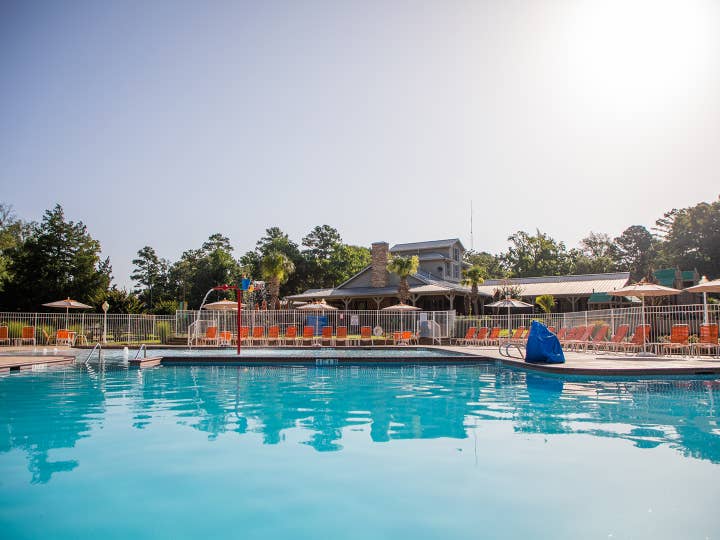 Outdoor springcreek pool surrounded by red pool chairs at Villages Resort in Flint, Texas