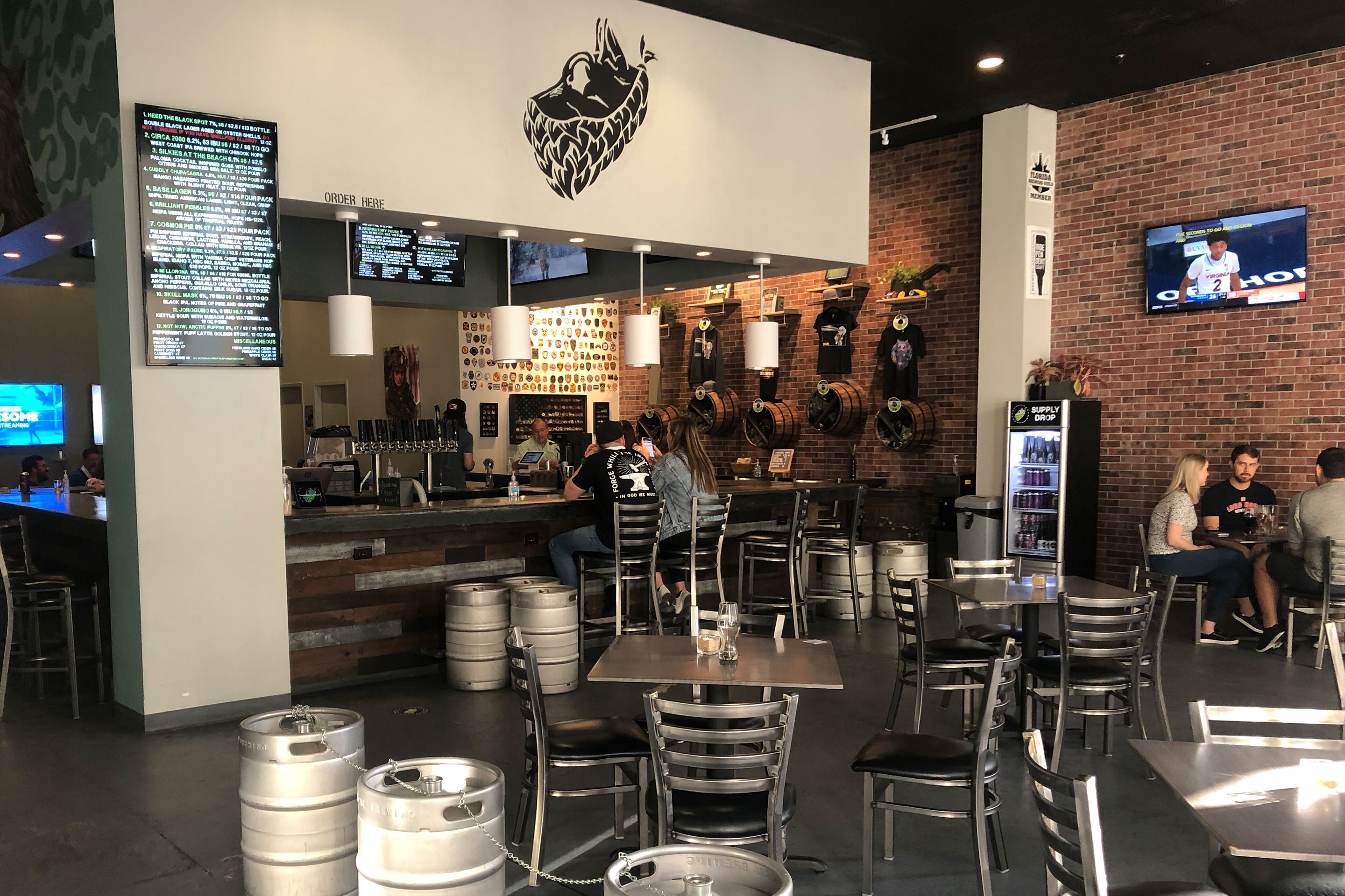 Interior of 'Tactical Brewing Co.' with various silver tables and kegs.