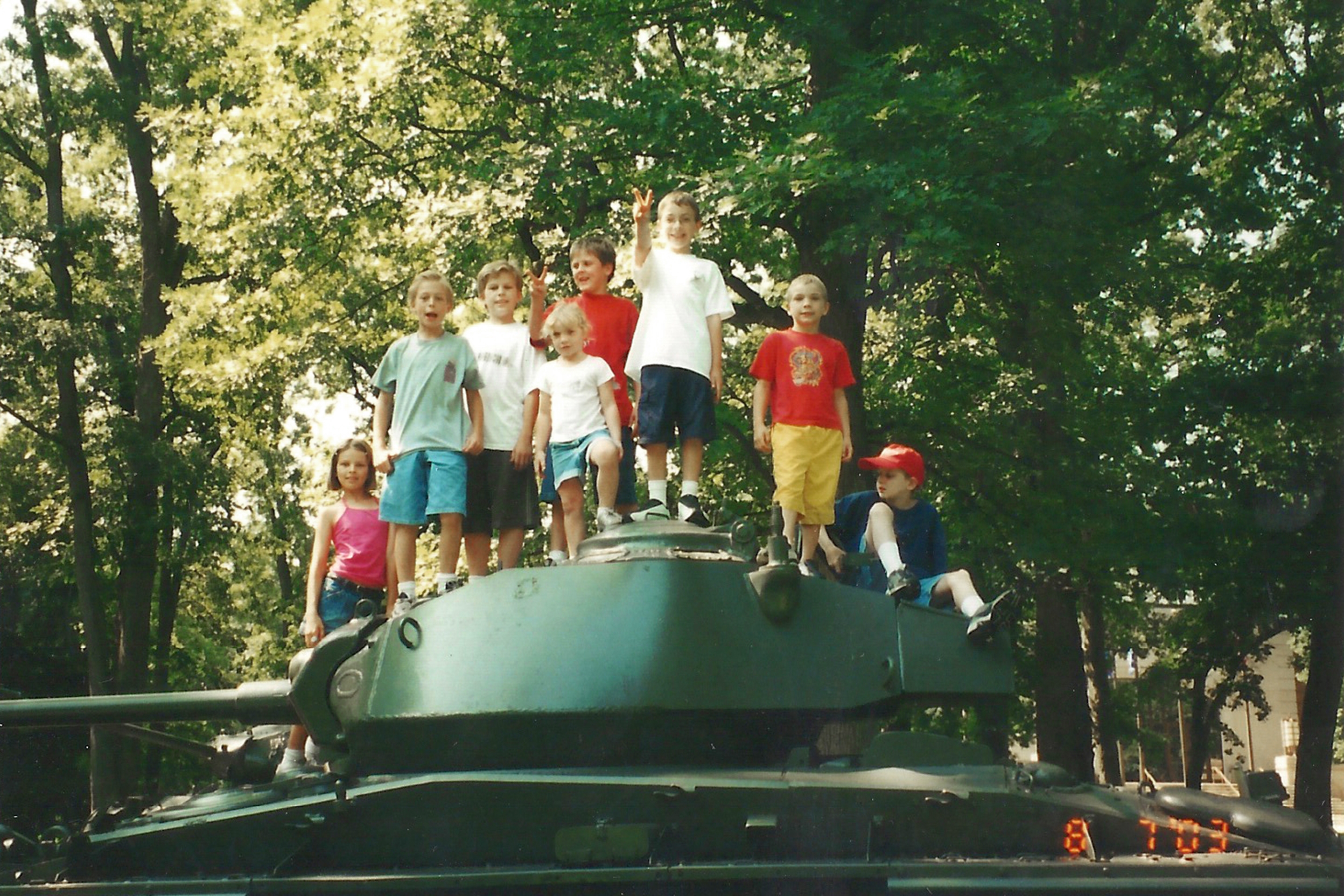 Several children stand on a retired US Army tank.
