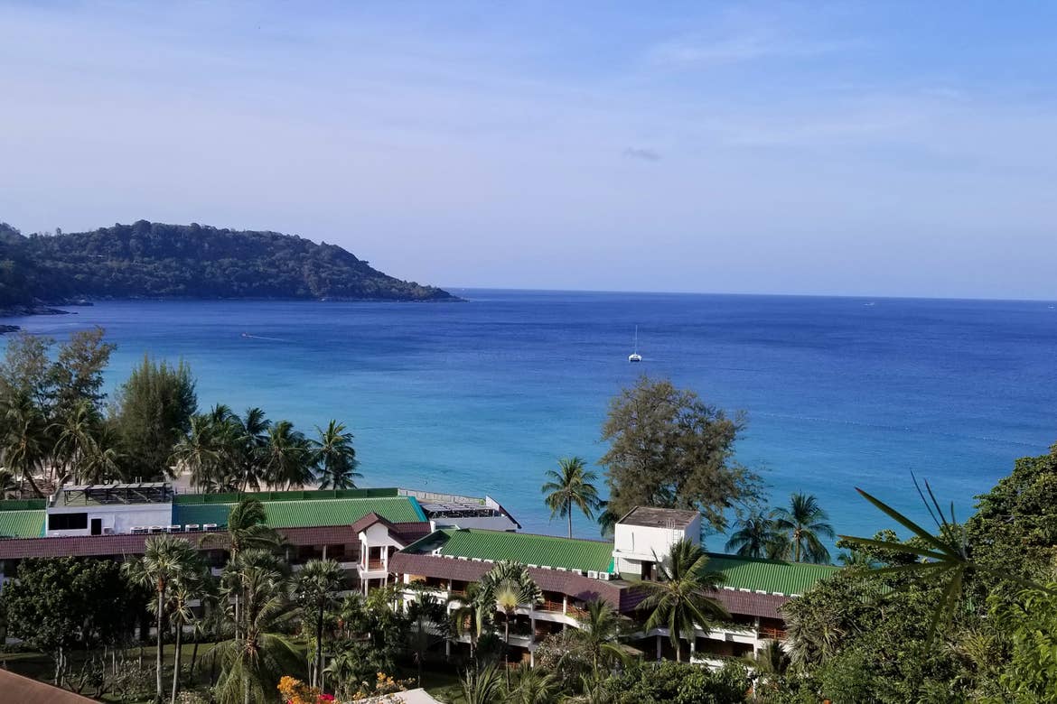 A overlook from a hotel balcony at the blue ocean waters and architecture of Phuket, Thailand