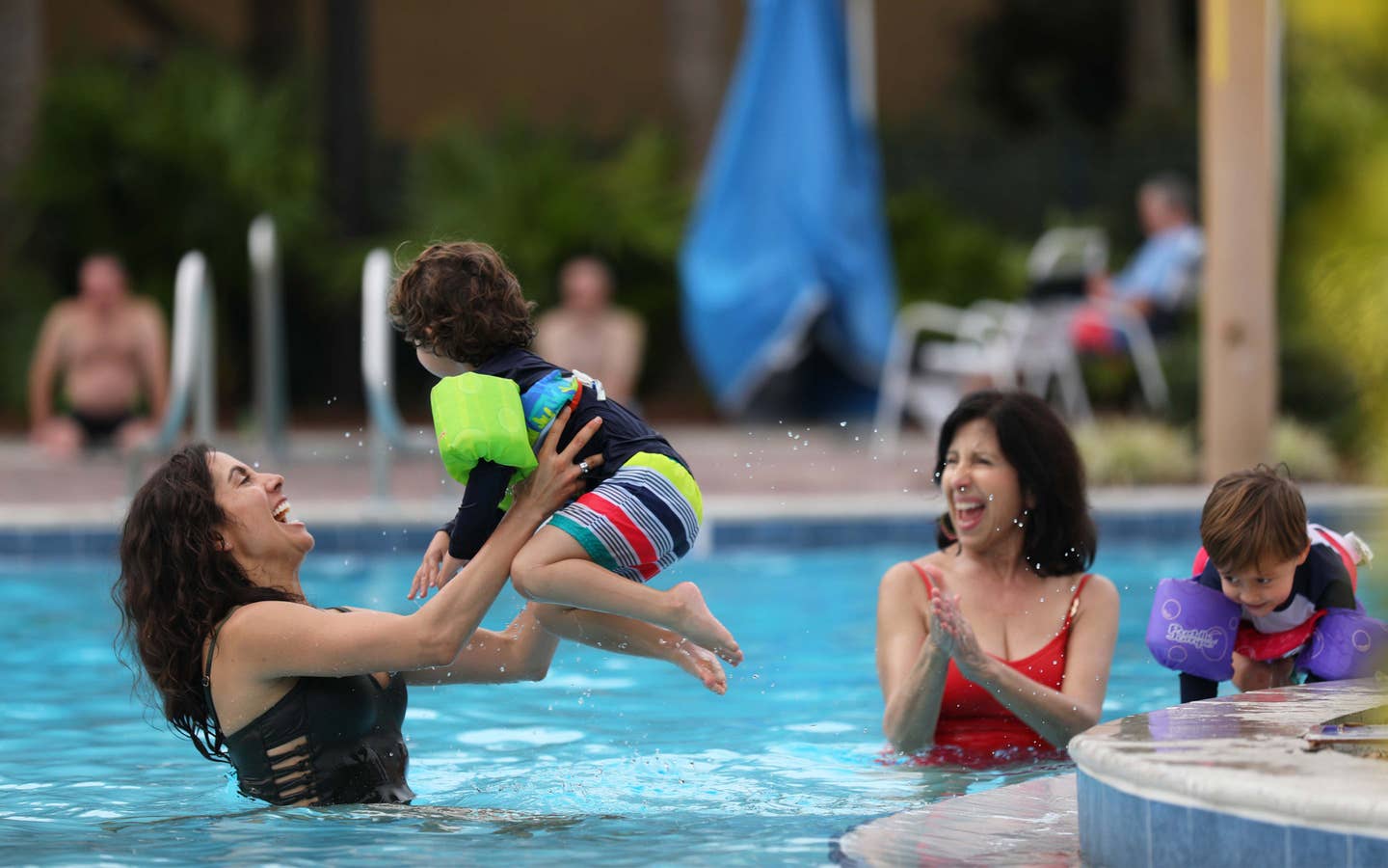 Mother playing with child in outdoor pool.
