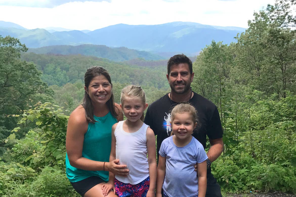 Author, Chris Johnston (far-left), stands in front of a range of trees at the Great Smoky Mountains with her husband, Josh (far-right), and daughters, Kyndall (front-left), and Kyler (front-right).