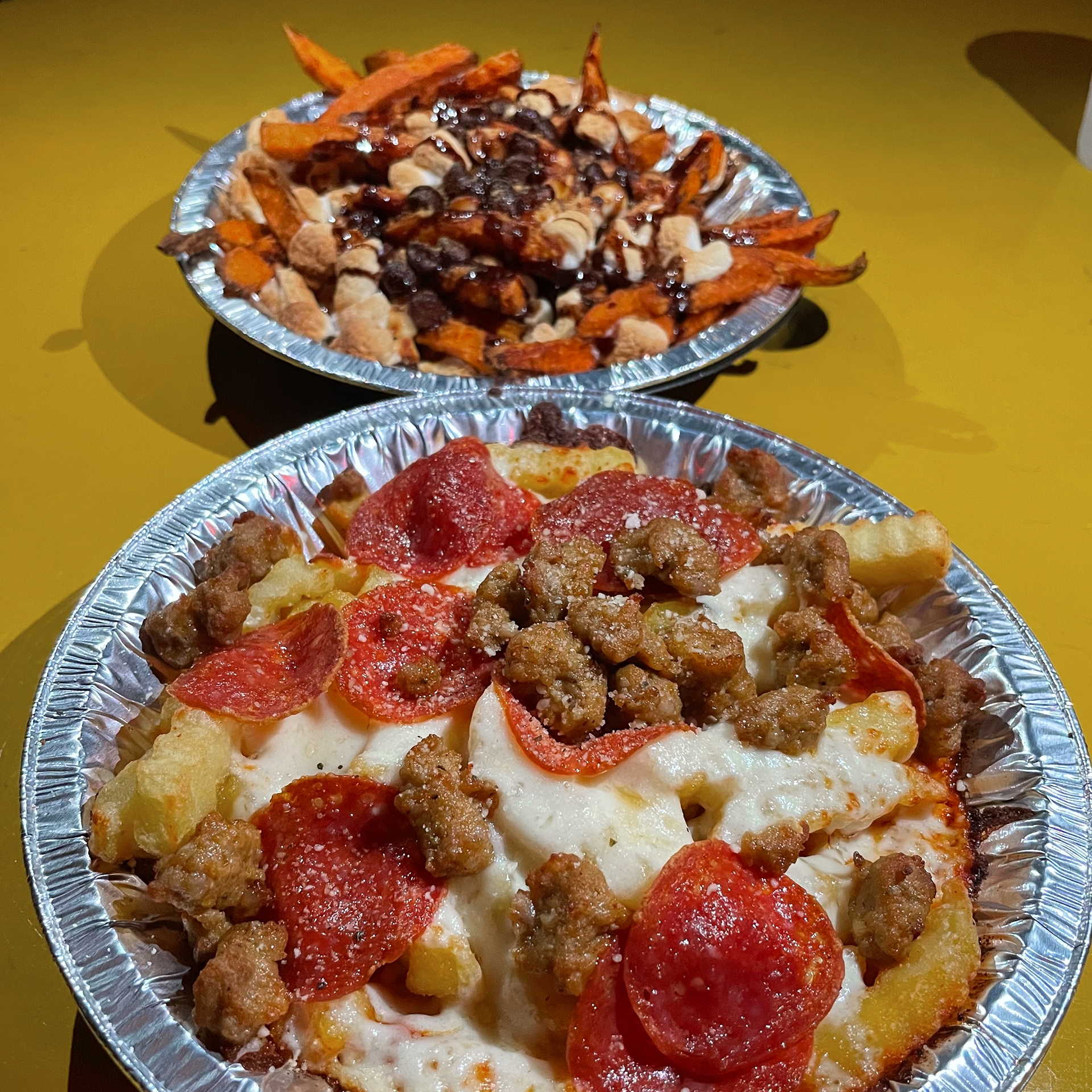 French fries with various toppings on a yellow table.