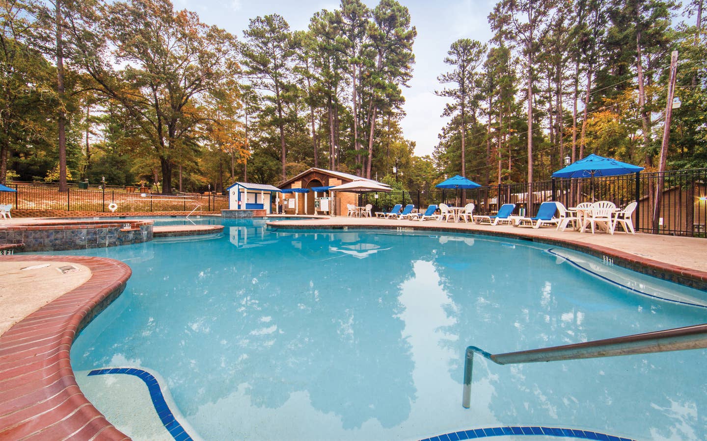 Outdoor pool with sun umbrellas at Holly Lake Resort in Texas.