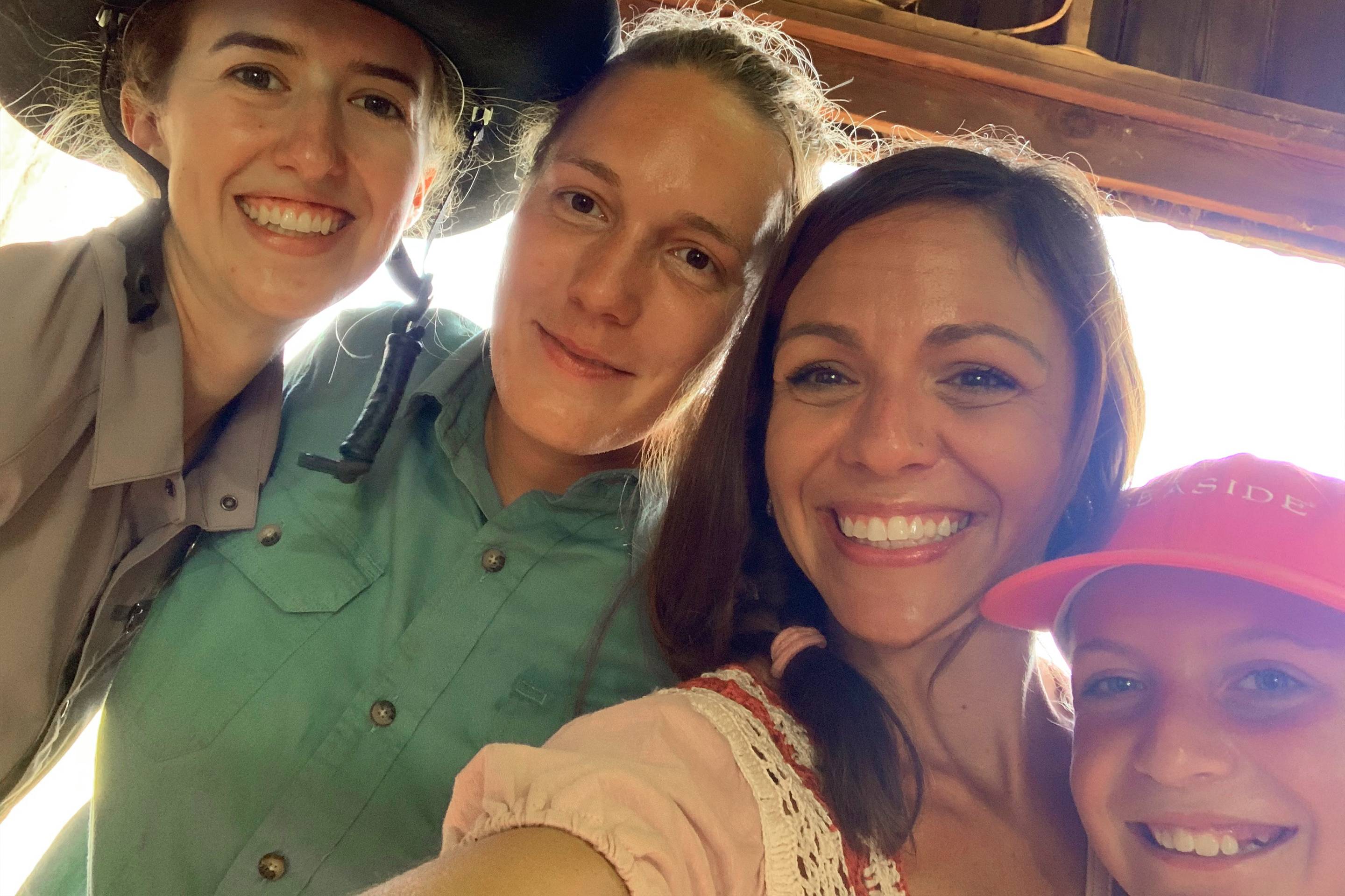 Four caucasian women stand in a horse stable.