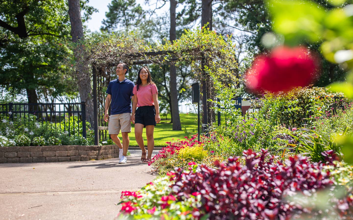 Two people walking through Tyler Rose Garden near Villages Resort in Flint, Texas.