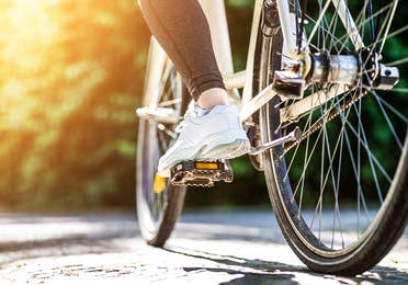 A person's foot on a pedal as they ride a bicycle.