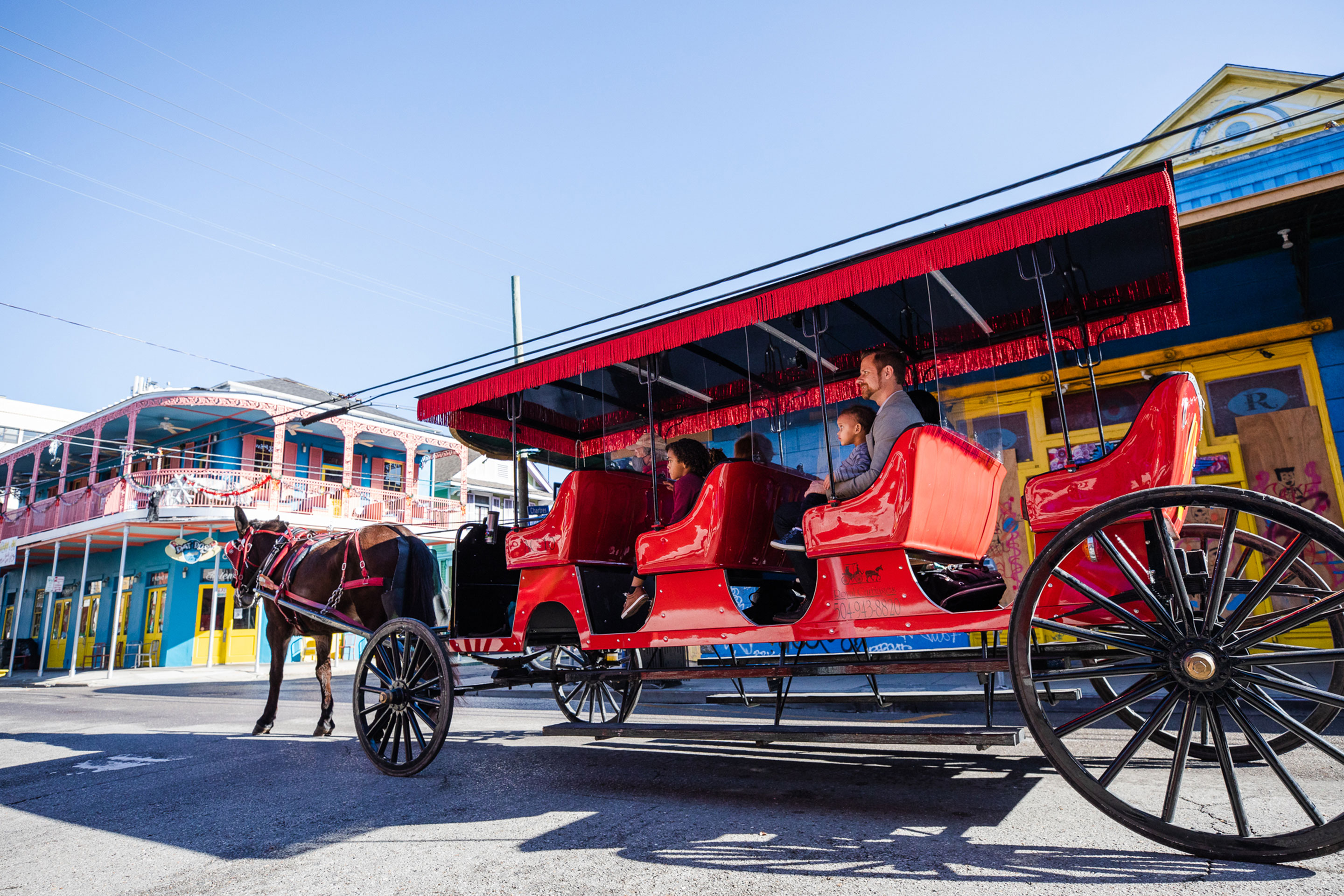 Featured Contributor, Sally Butan of @butanclan and her family  ride a red horse-drawn carriage through the streets of New Orleans, Louisiana.