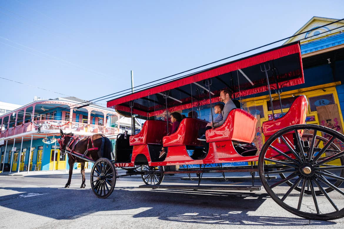 Featured Contributor, Sally Butan of @butanclan and her family ride a red horse-drawn carriage through the streets of New Orleans, Louisiana.