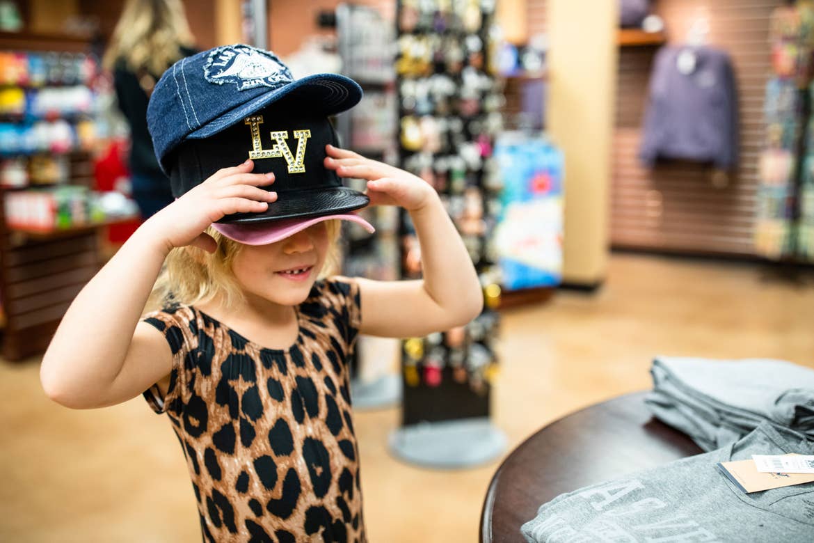 Tinsley Haby shops in the marketplace of our Desert Club Resort located in Las Vegas, Nevada wearing several black baseball hats that read, 'LV.'