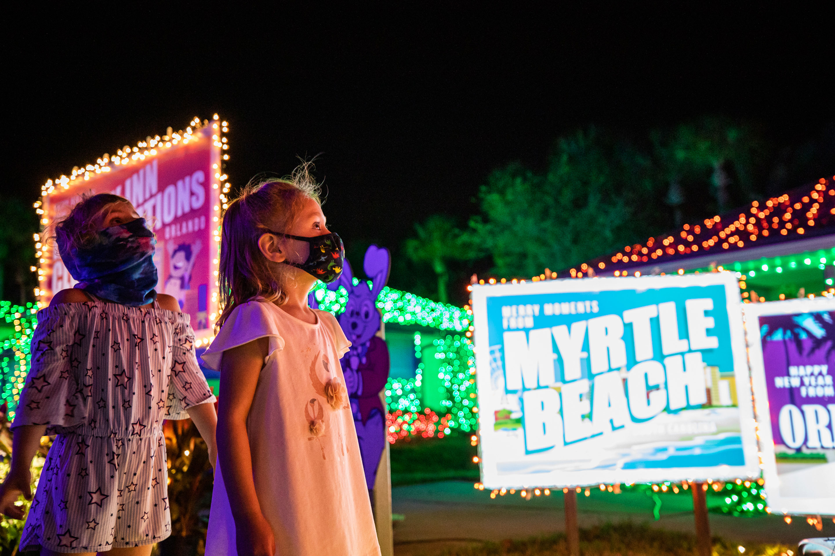 Three children from the Dowie Member Family look at the HICV villa decor wearing face masks.