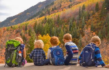 Jessica's kids sitting on the edge of a rock in front of gorgeous fall foliage and mountainous landscapes