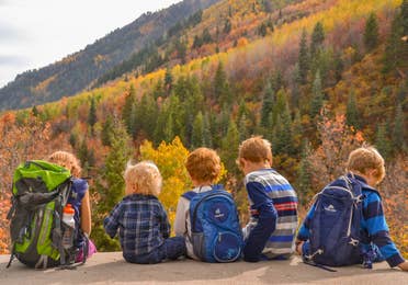 Jessica's kids sitting on the edge of a rock in front of gorgeous fall foliage and mountainous landscapes