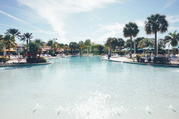Outdoor pool with beach chairs surrounded by palm trees in West Village at Orange Lake Resort near Orlando, Florida