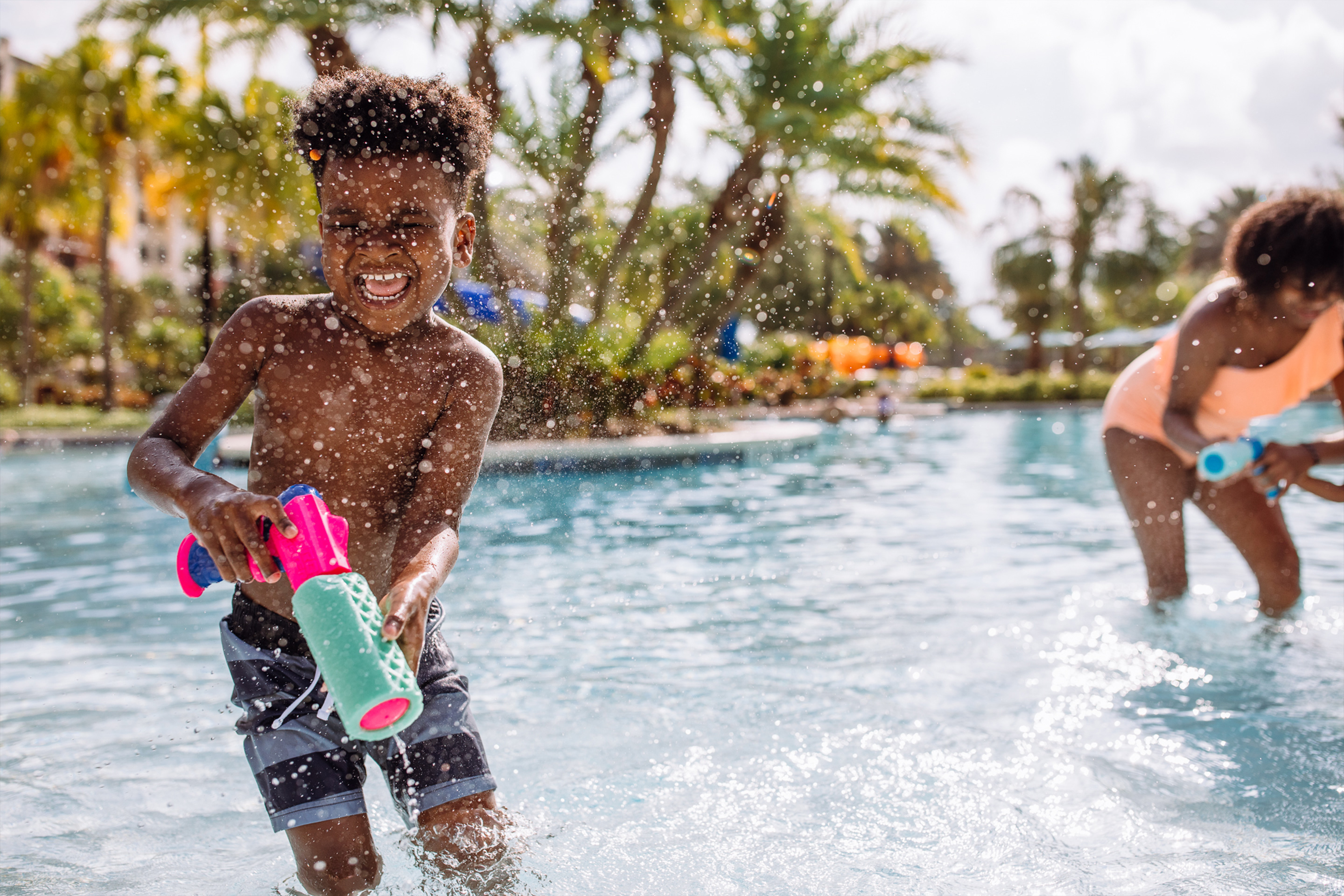 Krystin Godfrey's son, Joshua (left) gets splashed by Sabria's (right) squirt gun in the pool.
