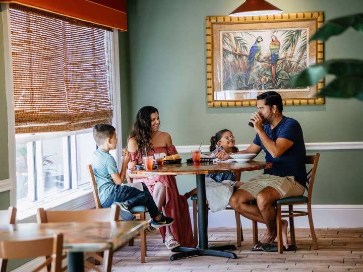 Family of four having a meal at Cape Grill & Bar at Cape Canaveral Beach Resort in Florida.