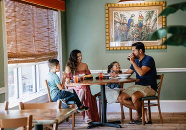 Family of four having a meal at Cape Grill & Bar at Cape Canaveral Beach Resort in Florida.