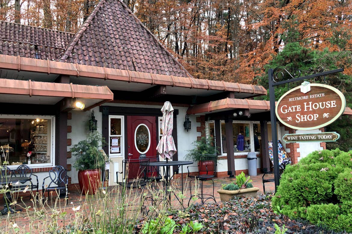 The exterior of a Gate House Shop near the Biltmore Estate with signage that reads, 'Biltmore Estate, Gate House Shop, Wine Tasting Today.'
