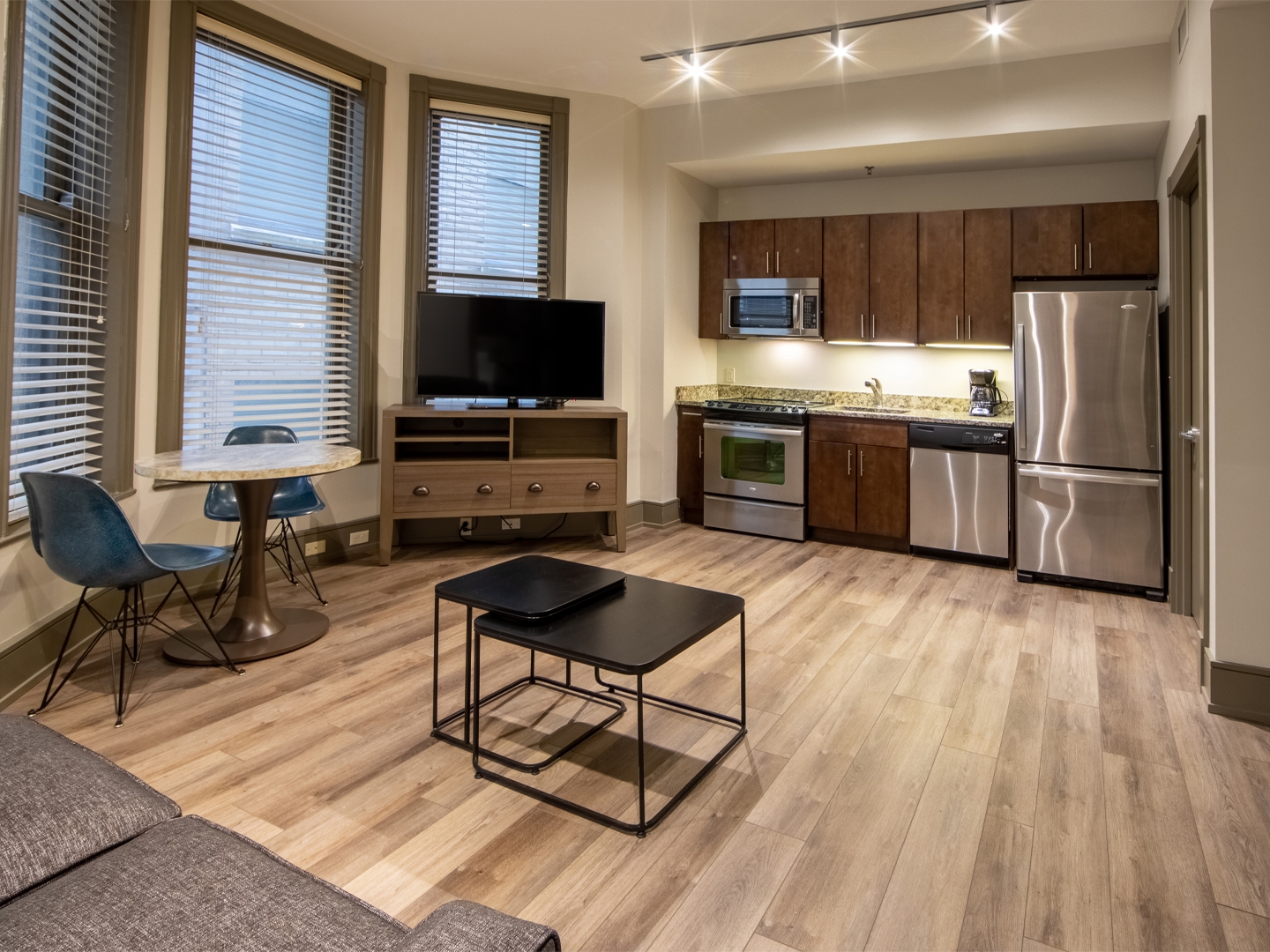 One bedroom villa living area with couch, three windows, TV and full kitchen at New Orleans Resort in Louisiana.
