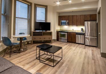 One bedroom villa living area with couch, three windows, TV and full kitchen at New Orleans Resort in Louisiana.