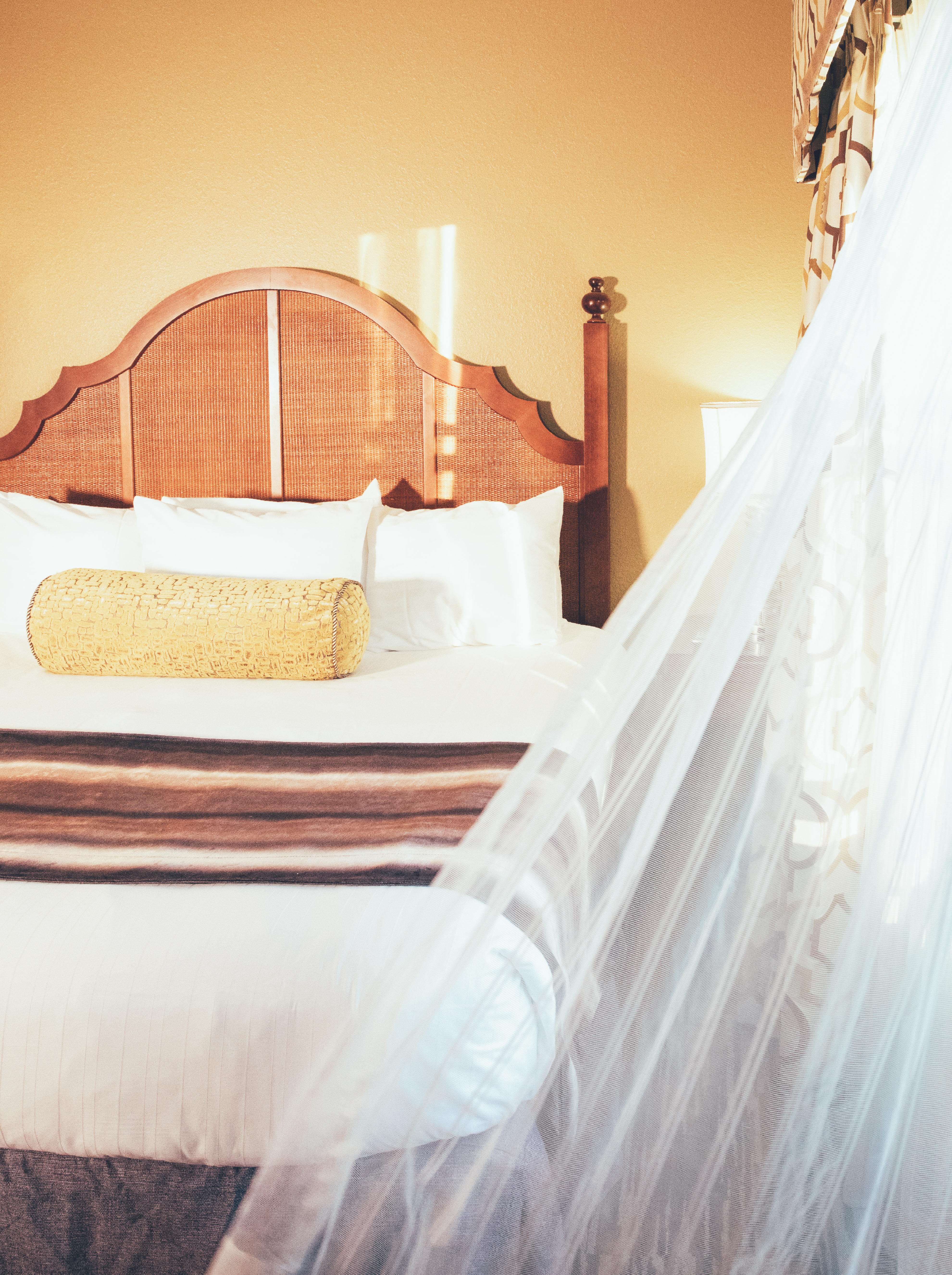 Closeup of curtain blowing into room and bed in background in a Signature villa in River Island at Orange Lake Resort near Orlando, Florida