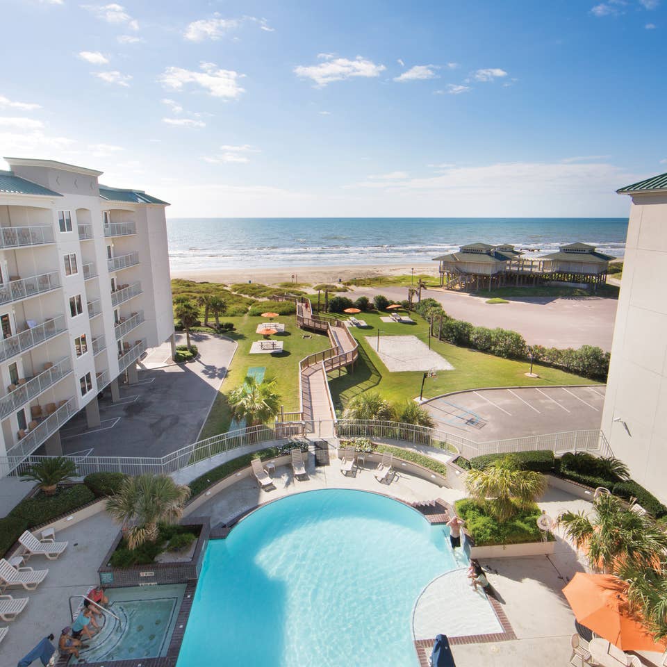View of outdoor infinity pool and beach from Galveston Beach Resort room balcony in Texas.