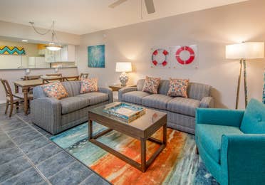 Living room with two couches, an accent chair, and coastal decor in a two-bedroom villa at Panama City Beach Resort