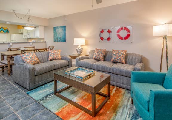 Living room with two couches, an accent chair, and coastal decor in a two-bedroom villa at Panama City Beach Resort