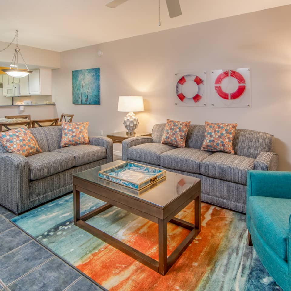 Living room with two couches, an accent chair, and coastal decor in a two-bedroom villa at Panama City Beach Resort