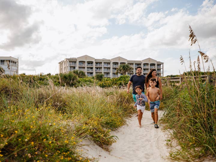 Family walking onto beach from Cape Canaveral Beach Resort in Florida.