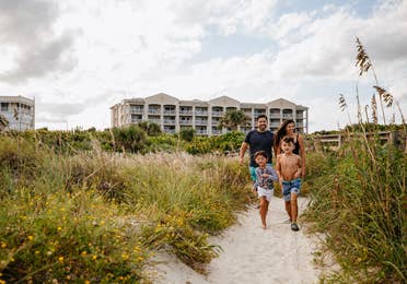 Family walking onto beach from Cape Canaveral Beach Resort in Florida.