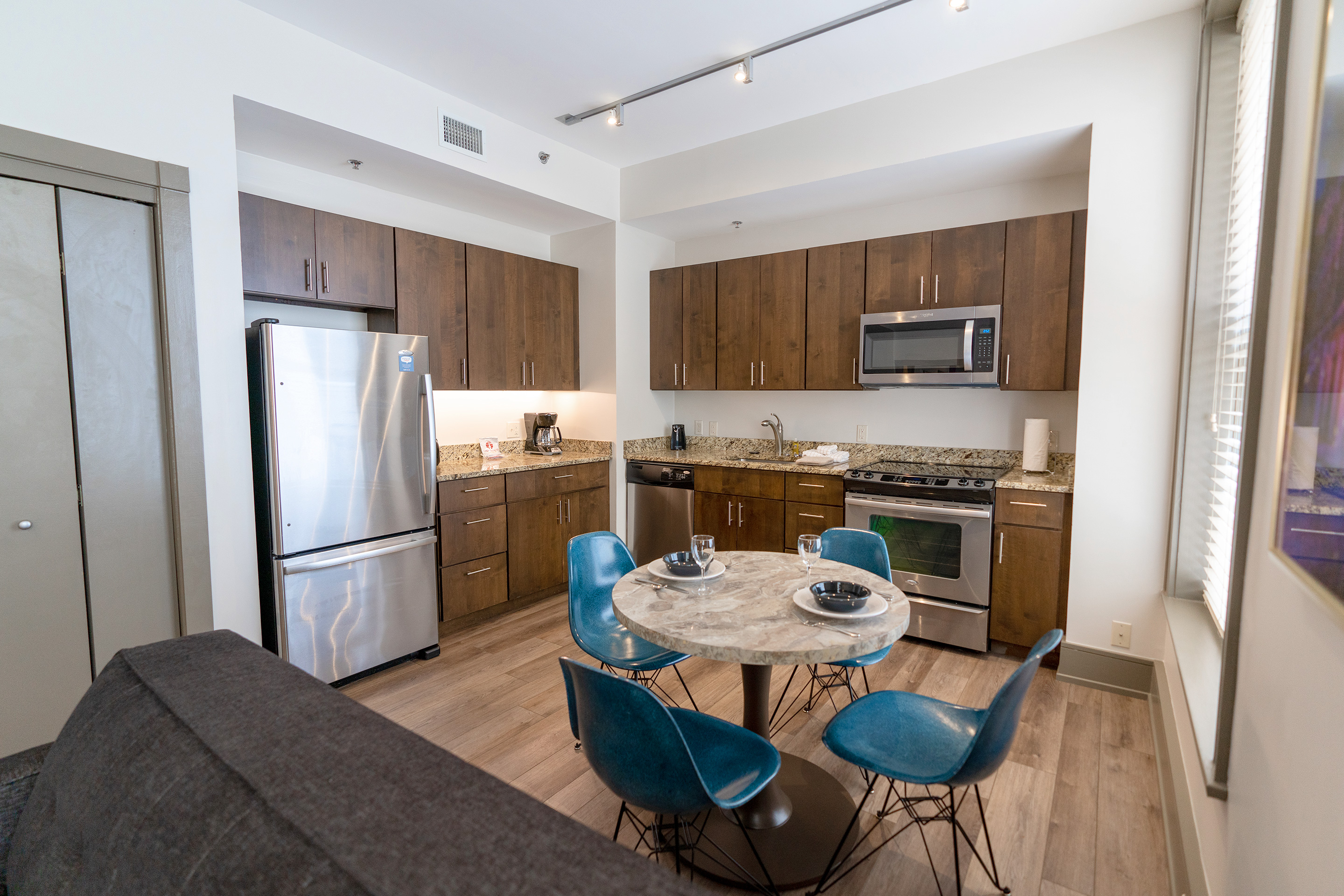 The interior of our one-bedroom standard villa at our New Orleans resort furnished with a round marble top dining table with four chair and two place settings near a kitchen area.