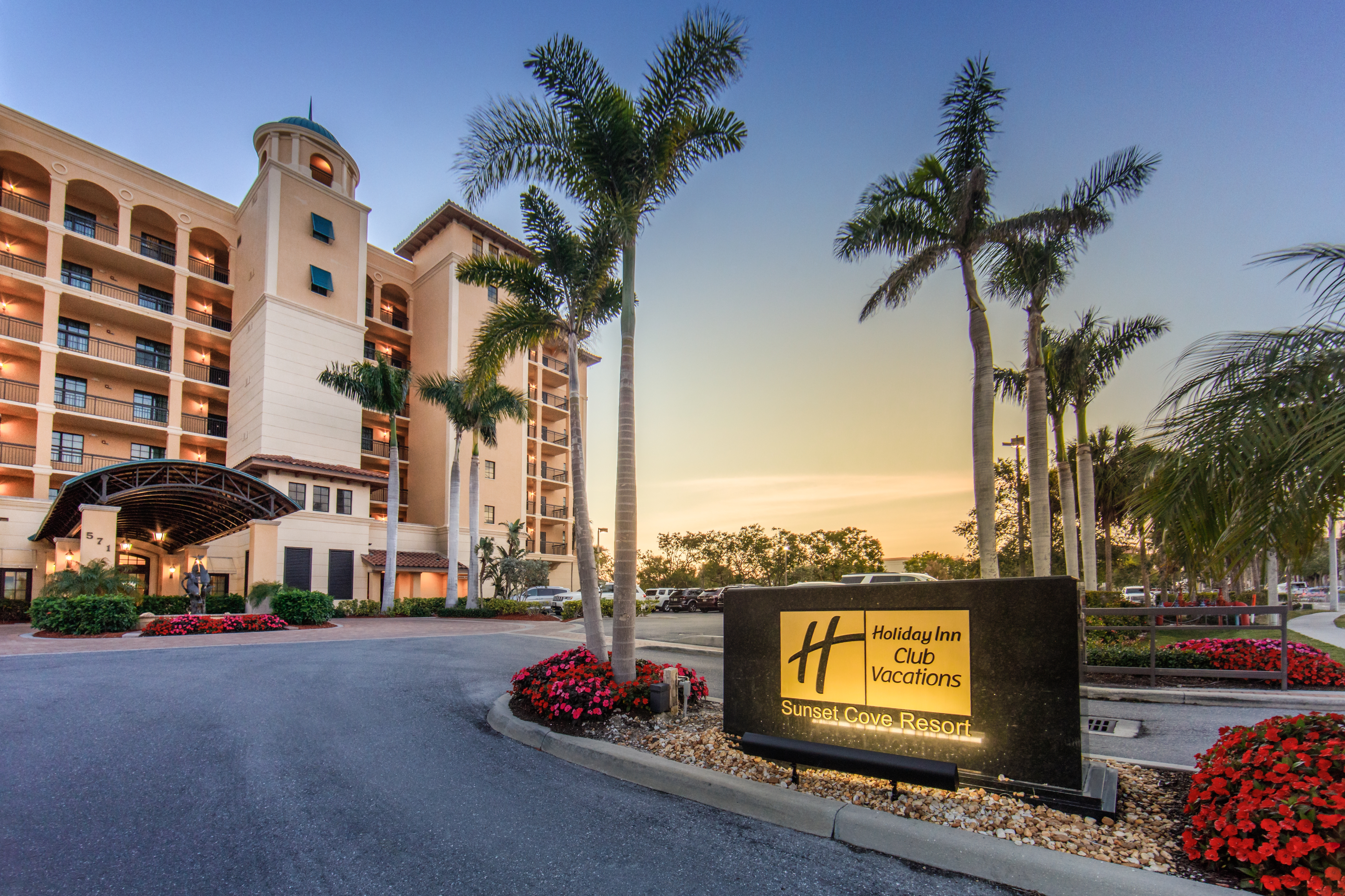 Property sign and building surrounded by palm trees at Sunset Cove Resort in Marco Island, Florida.