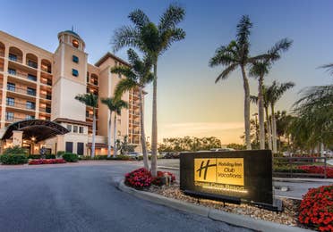 Property sign and building surrounded by palm trees at Sunset Cove Resort in Marco Island, Florida.