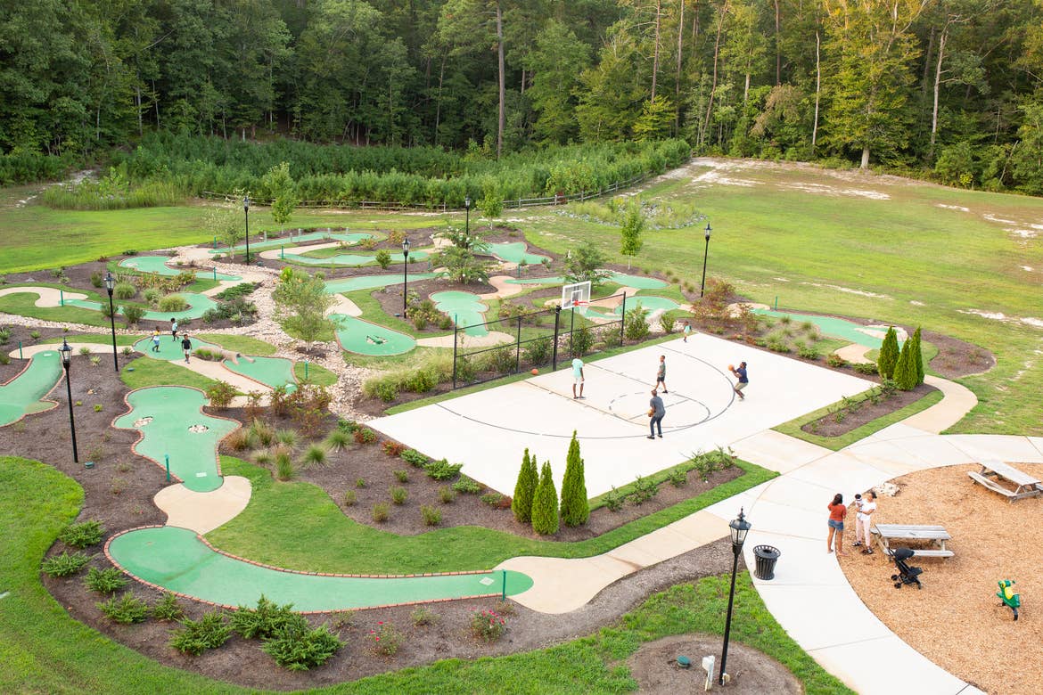 Families enjoying outdoor amenities such as mini-golf and basketball surrounded by lush landscapes at our Williamsburg resort in Williamsburg, Virginia.