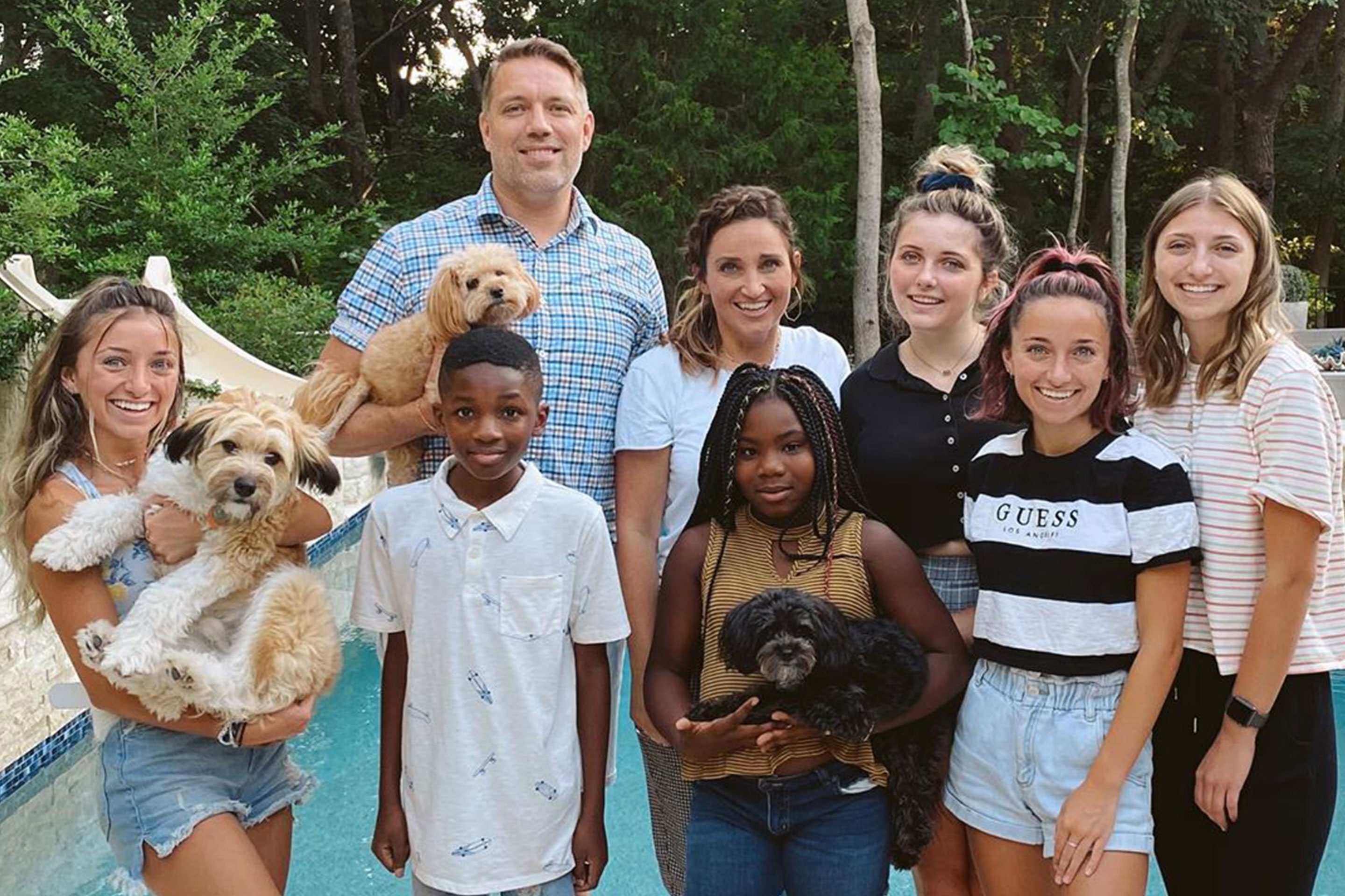 Mindy and her family pose in front of their pool with some of their pets.