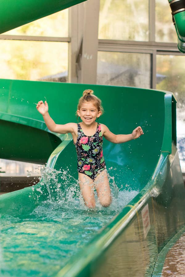 Child walking out of bottom of green waterslide at Waterpark at the Villages in Flint, Texas.