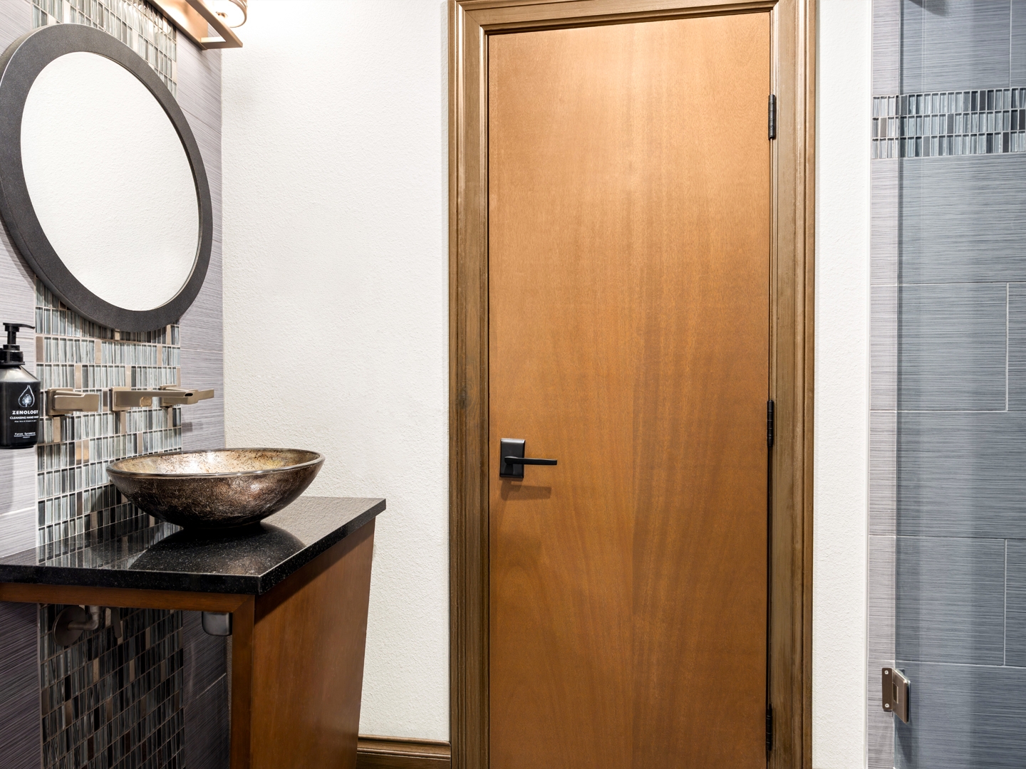 Modern bathroom with glass shower and gold accents.
