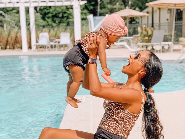Adult holding baby in air by the outdoor pool at Williamsburg Resort.