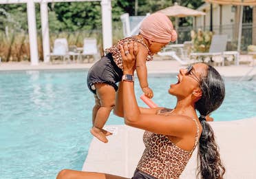 Adult holding baby in air by the outdoor pool at Williamsburg Resort.