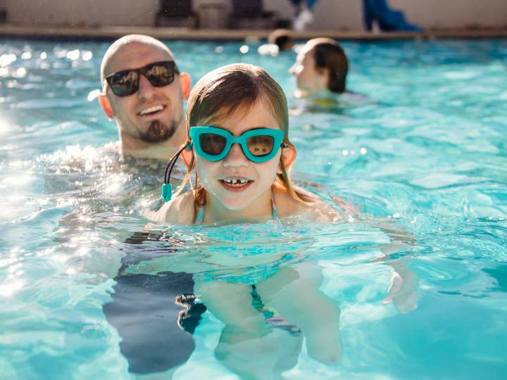 Father and daughter swimming in outdoor pool at Desert Club Resort in Las Vegas, Nevada.