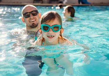 Father and daughter swimming in outdoor pool at Desert Club Resort in Las Vegas, Nevada.